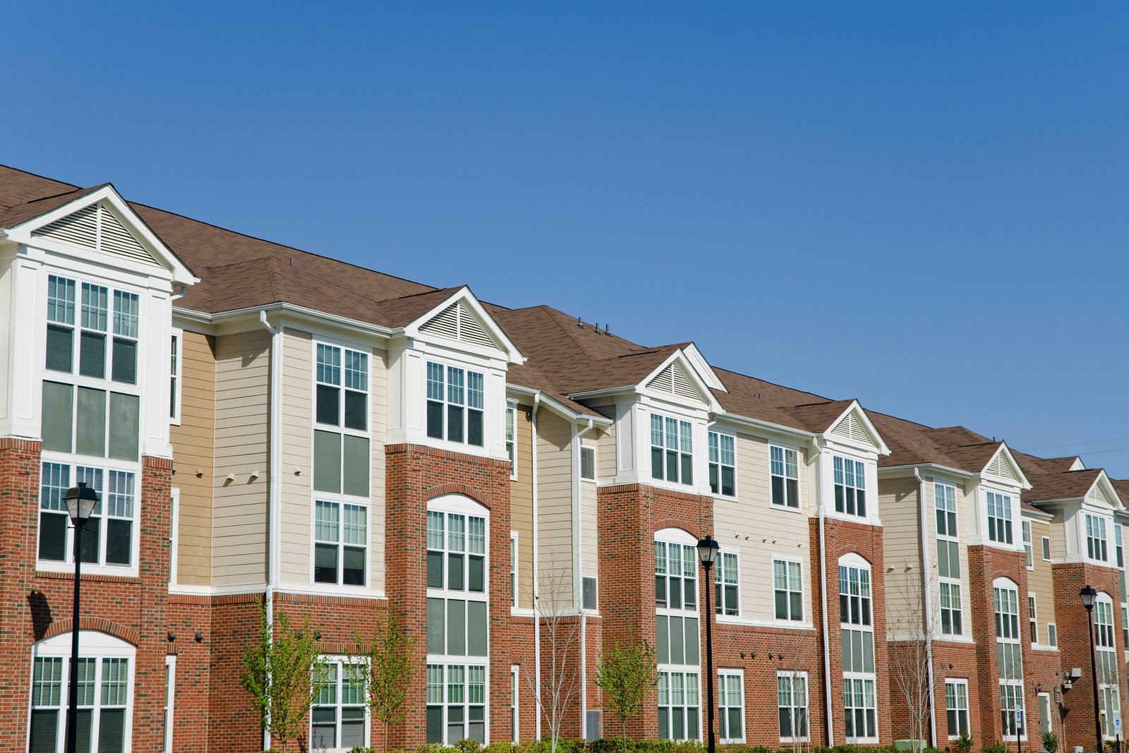 Brick and clapboard garden-style apartment buildings under a clear sky