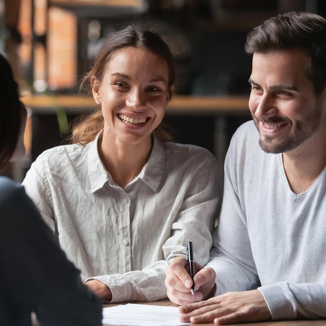 smiling couple signing lease with leasing agent