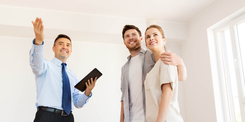 couple and realtor with tablet pc at new home