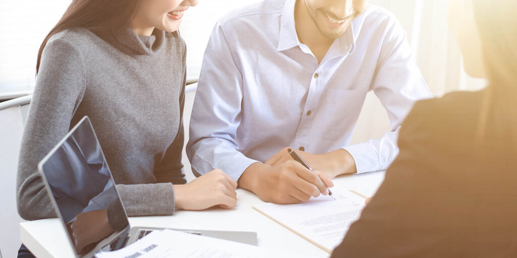 Couples made signing real estate leases, they have smilly and happy faces.